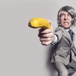 A man holding a banana as though it were a lethal weapon.
