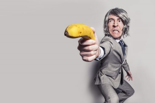 A man holding a banana as though it were a lethal weapon.