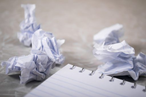 A notepad next to scrunched up balls of paper, symbolizing data that is no longer needed.