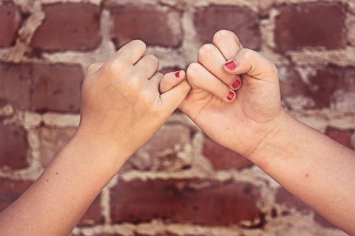 Two girls performing a "pinky promise" ritual with their hands.