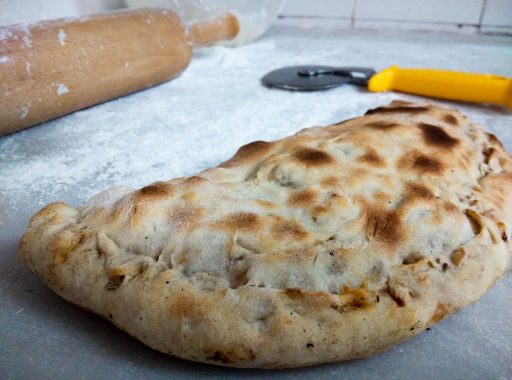 A calzone pizza being prepared in a kitchen.
