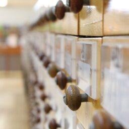 An old-fashioned directory system with paper records in wooden drawers at a library.